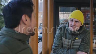 两名身穿<strong>保暖</strong>泡泡夹克的男运动员在咖啡馆户外训练后聊天的特写镜头